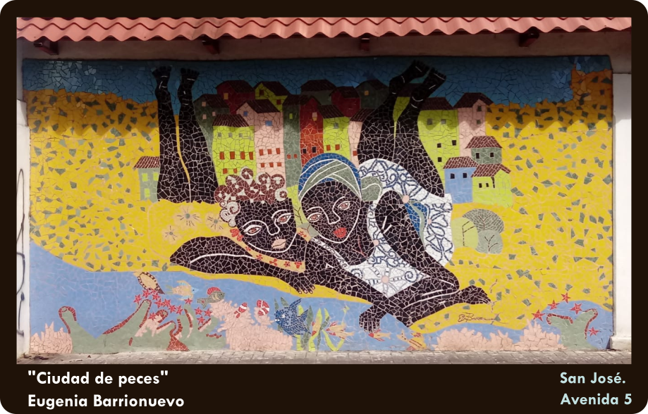 Mural que muestra a dos niñas afrodescendientes recostadas en el suelo frente a un arroyo en donde juegan con algunos peces. A sus espaldas algunas casas